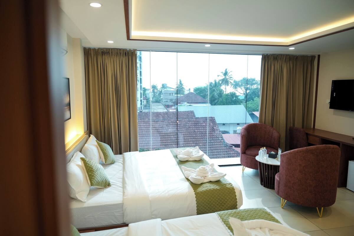A hotel room with a bed, two chairs, a small table, and a TV.