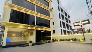 A modern building with multiple floors, large windows, and a sign indicating a hotel. - Hotel Calicut Beach Annex (Kozhikode)