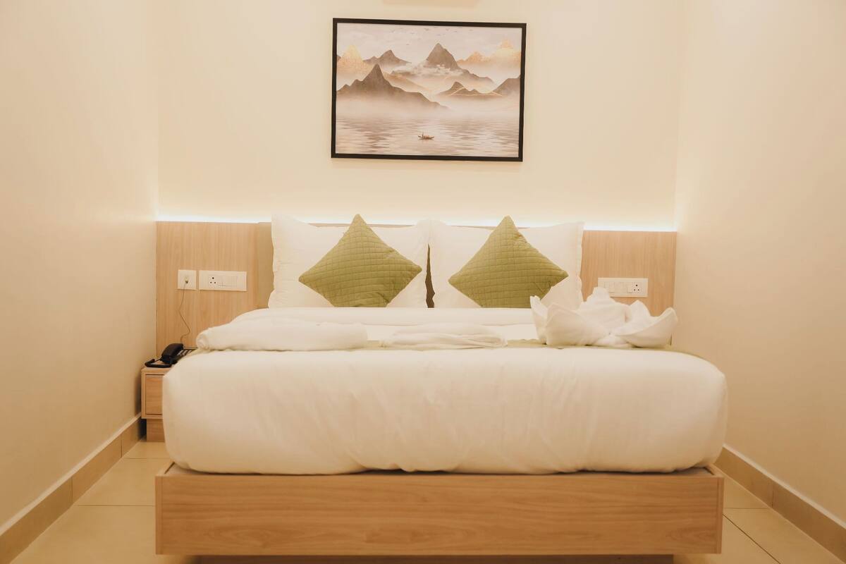 A modern hotel room with a bed, bedside table, and a framed artwork on the wall.