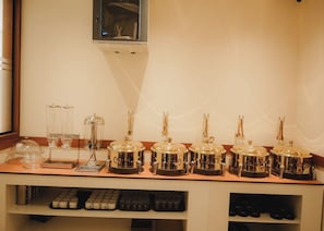 A bar area with a row of coffee dispensers, a coffee machine, and a wine cooler. - Hotel Calicut Beach Annex (Kozhikode)