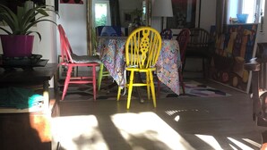 A room with a mirror, a table with chairs, a potted plant, and artwork on the walls. - Quiet artist's house with stunning lake view. (Tresserve)