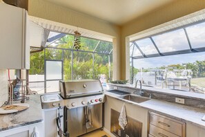 A kitchen with a grill, sink, and large windows overlooking a garden. - Fish, Grill + Chill: Port Charlotte Escape (Port Charlotte)
