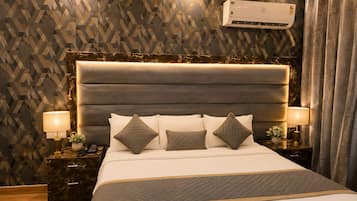 A bedroom with a large bed, headboard, bedside tables, lamps, and a patterned wall.