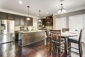 A kitchen with dark wood flooring, stainless steel appliances, and a central island with seating. - Spacious Group Hub! Walk to Tribble Mill Park (Lawrenceville)