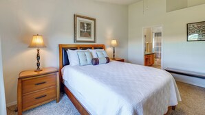 Una camera da letto con un letto, due comodini, una ventola a soffitto, un quadro appeso al muro e uno specchio.