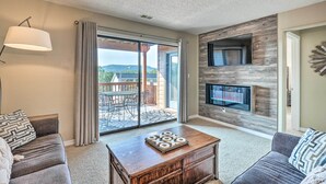 Ein Wohnzimmer mit Kamin, Fernseher und Blick ins Freie.