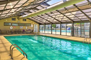 An indoor swimming pool with a glass ceiling, clear water, and a view of the outside. - Pool Access! 2-Unit Escape at Pointe Royale Resort (Branson)