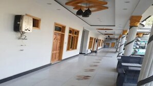 A hallway with patterned floor tiles, wooden doors, and ceiling fans.