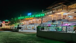 A multi-story building with a sign reading 'Holiday Inn Kalam.'