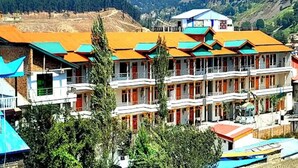 A multi-story building with balconies, set against a mountainous backdrop.