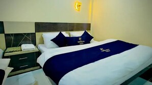 A hotel room with a bed, a nightstand, and a wall-mounted light fixture.