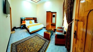A bedroom with a bed, a ceiling fan, a wooden wardrobe, a mirror, and a television.