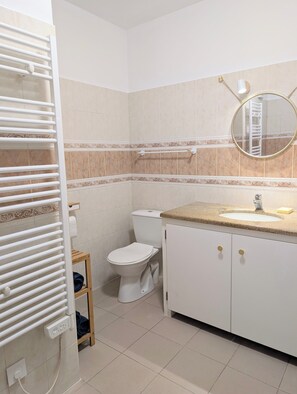 A bathroom with a toilet, sink, mirror, towel rack, and a radiator. - T3 ground floor facing maquis, quiet, close to beaches and mountains (Alata)