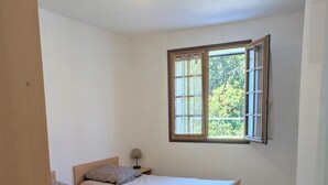 Un dormitorio con dos camas, una ventana con cortinas, una lámpara de noche y una luz en el techo.