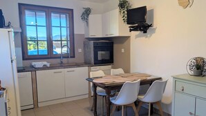 Una cocina con una mesa de comedor, sillas, un televisor y una ventana.
