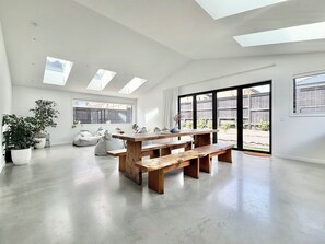 A spacious room with skylights, a wooden bench, and a large window. - Stylish Alpine Winter Retreat • Large, Warm, Modern & Peaceful (Jack's Point)