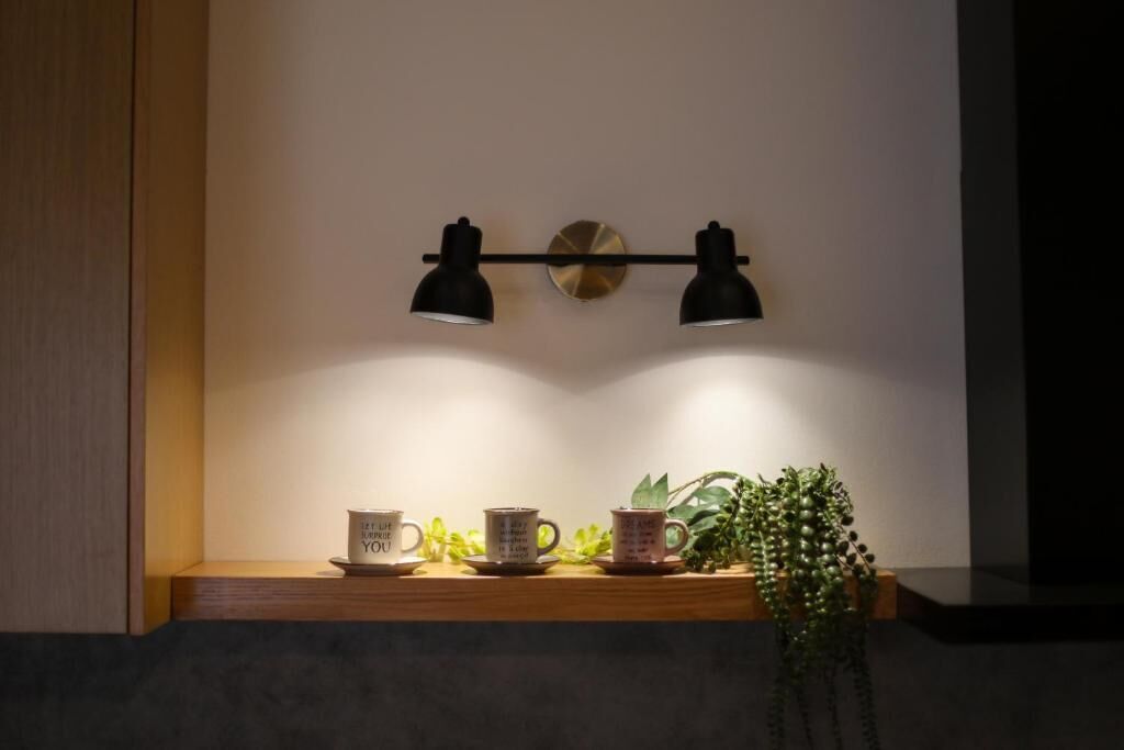 A shelf with two mugs, a potted plant, and a wall-mounted light fixture.