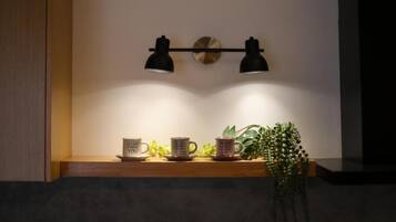 A shelf with two mugs, a potted plant, and a wall-mounted light fixture.