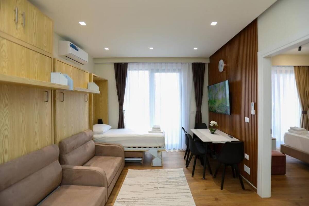 A hotel room with a bed, a sofa, a desk, and a TV.