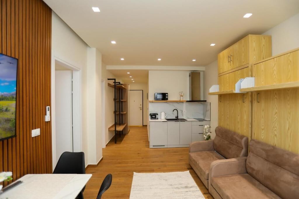 Una sala moderna con un sofá, una mesa de comedor y una cocina al fondo.
