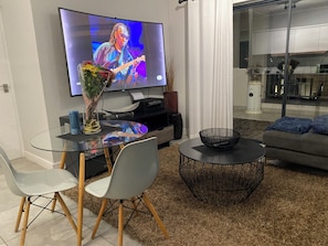 Ein modernes Wohnzimmer mit einem Flachbildfernseher, einem Glastisch und einer Couch.