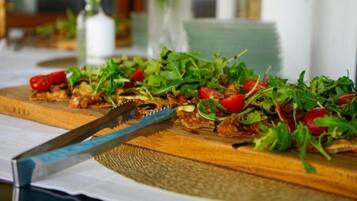 Een houten snijplank met een salade, een mes en een onscherpe achtergrond.