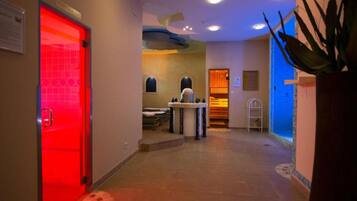 A hotel hallway with a red door, a reception desk, and a plant.