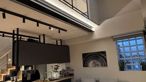 A modern interior with a kitchen, dining area, and a loft space. - Kirki Luxury Loft (Athina)