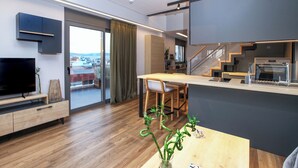 A modern kitchen with a dining area, a TV, and a view of the city. - Kirki Luxury Loft (Athina)