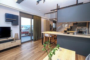 A modern kitchen with a dining area, a TV, and a view of the city. - Kirki Luxury Loft (Athina)