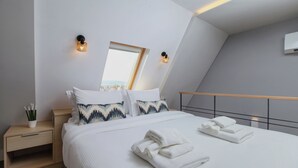 A modern bedroom with a bed, bedside tables, a nightstand, a mirror, and a view of the city. - Kirki Luxury Loft (Athina)