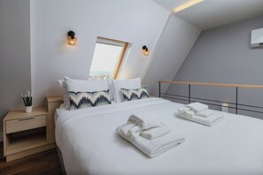 A modern bedroom with a bed, bedside tables, a nightstand, a mirror, and a view of the city. - Kirki Luxury Loft (Athina)