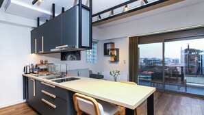 A modern kitchen with a large island, wooden flooring, and a view of the city through large windows. - Kirki Luxury Loft (Athina)