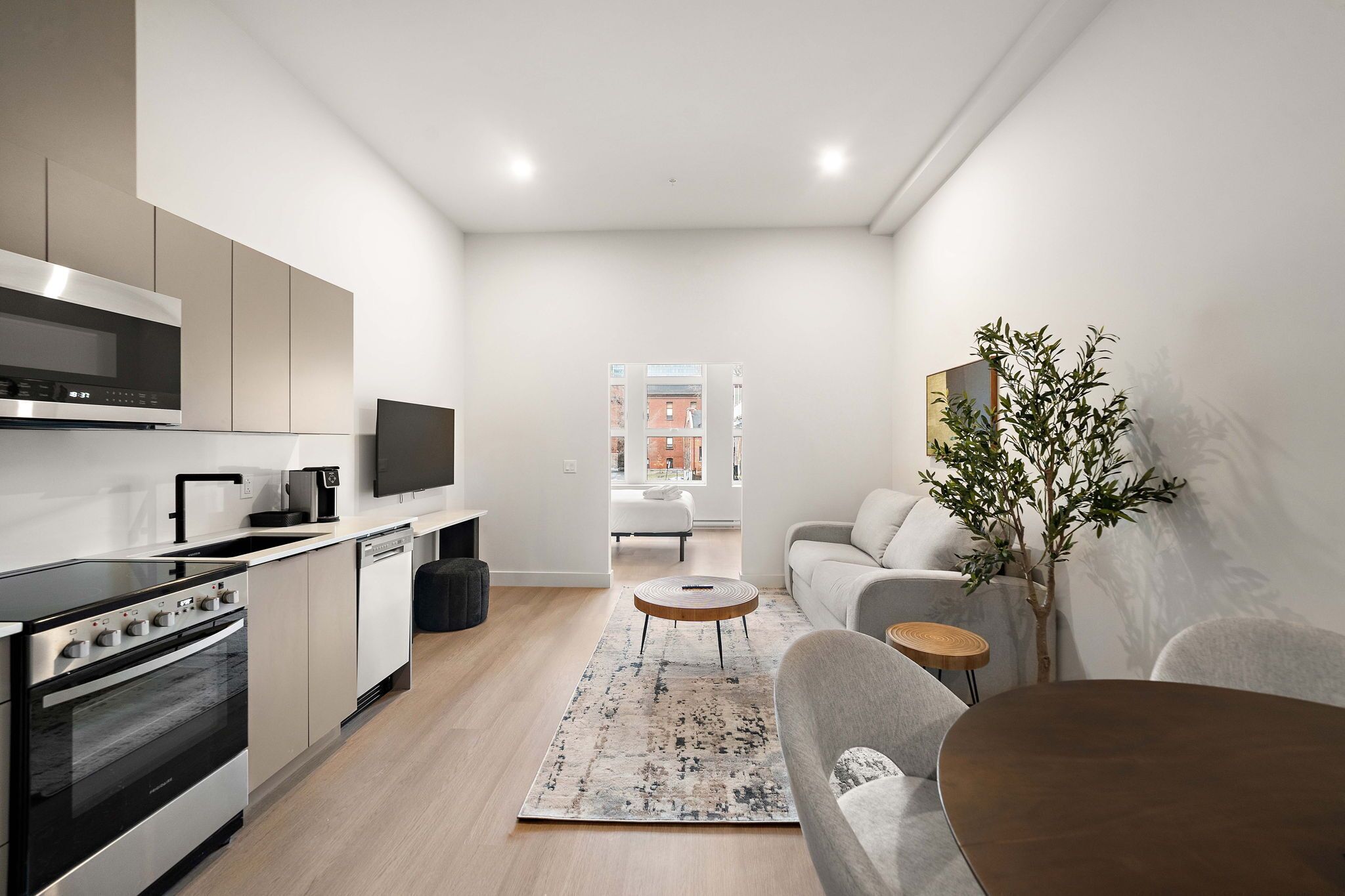 Una cucina moderna con forno e microonde integrati, una zona pranzo con tavolo e sedie rotonde, e un soggiorno con divano e tavolino.