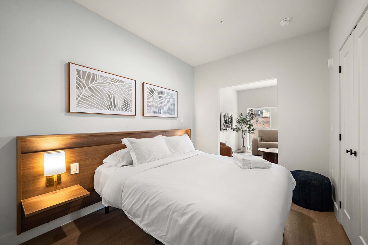 Ein modernes Hotelzimmer mit einem großen Bett, Nachttischlampen und zwei gerahmten Wandbildern.
