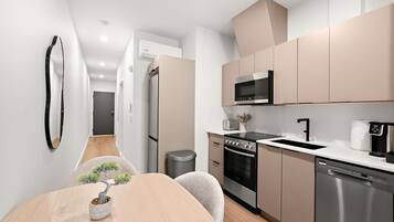 Une cuisine moderne équipée d’appareils électroménagers en acier inoxydable, un coin repas avec une table et des chaises en bois, et une petite plante en pot.
