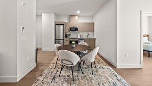 A modern kitchen with a dining area, featuring a round table, chairs, and a kitchen island. - Nomade Saint Paul (Montréal)