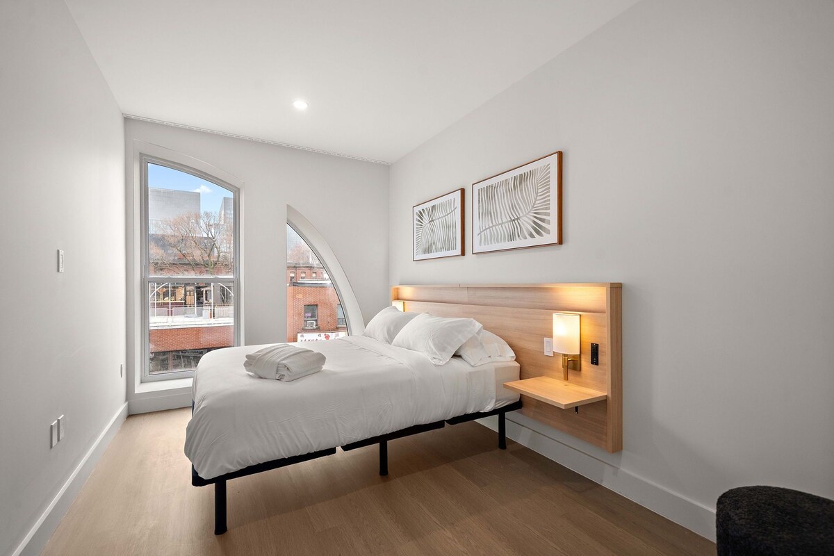 Ein modernes Schlafzimmer mit Bett, Nachttisch und Kunstwerk.