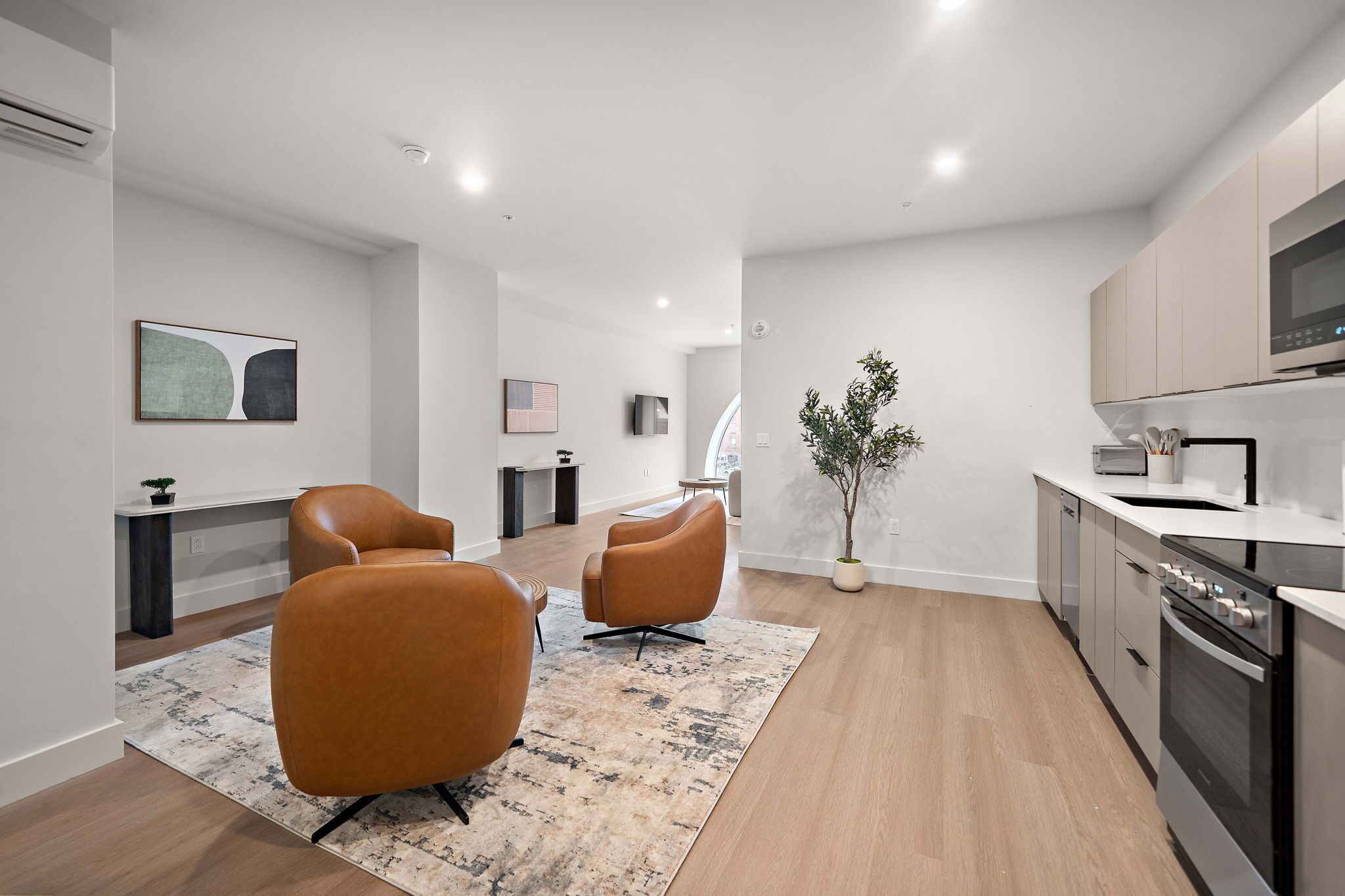 Una sala moderna con dos sillones de cuero, un comedor con mesa y una cocina con horno empotrado.
