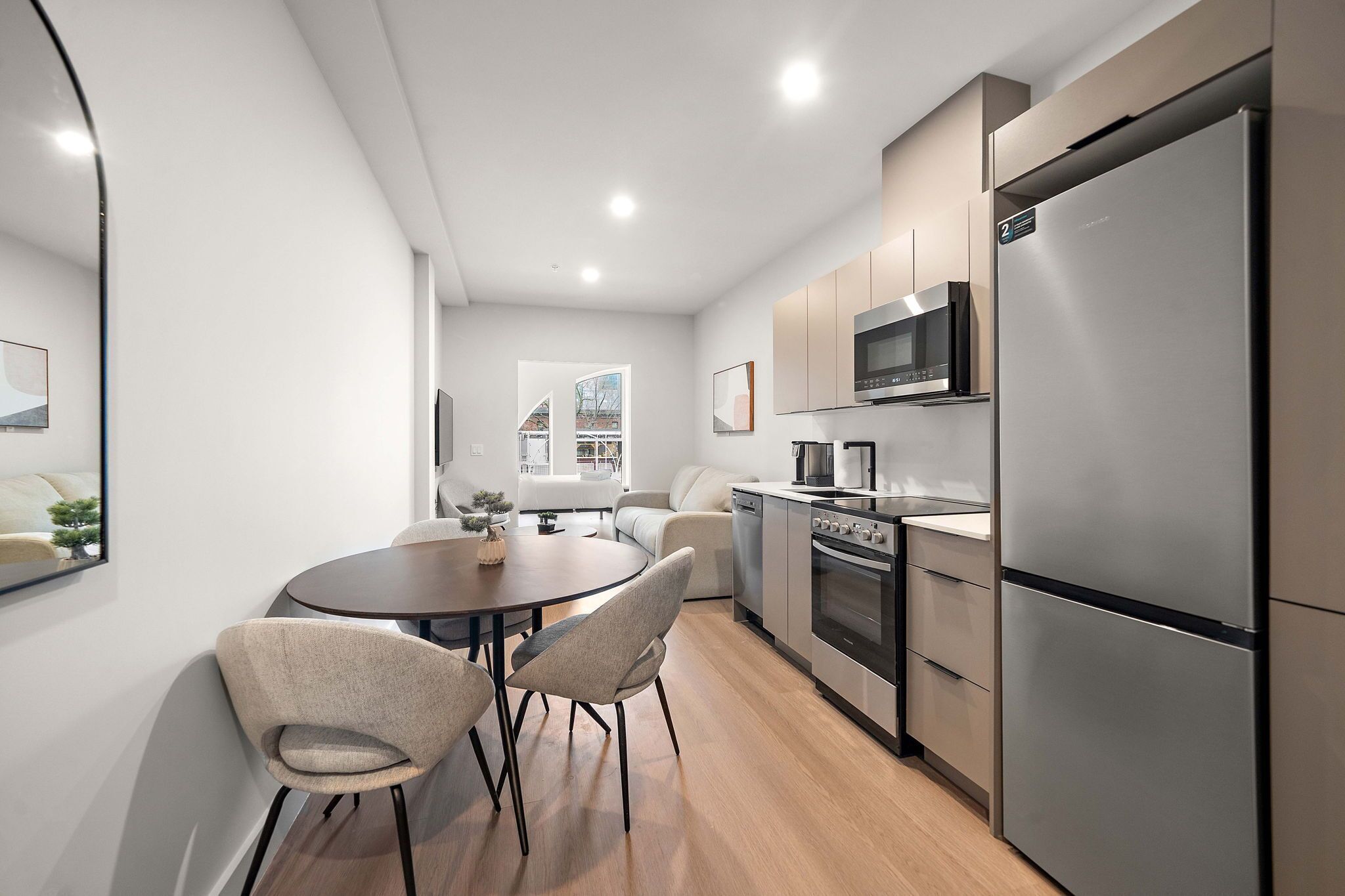 A modern kitchen with a dining area, stainless steel appliances, and a view of the city.