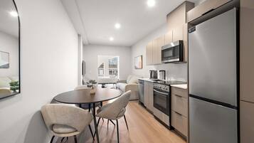 A modern kitchen with a dining area, stainless steel appliances, and a view of the city.
