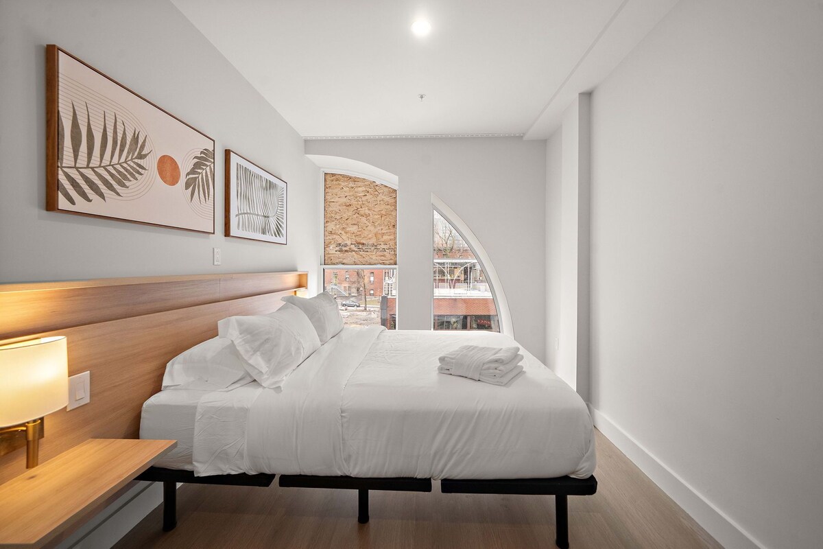 Ein modernes Schlafzimmer mit Bett, Nachttisch und Wandbild.