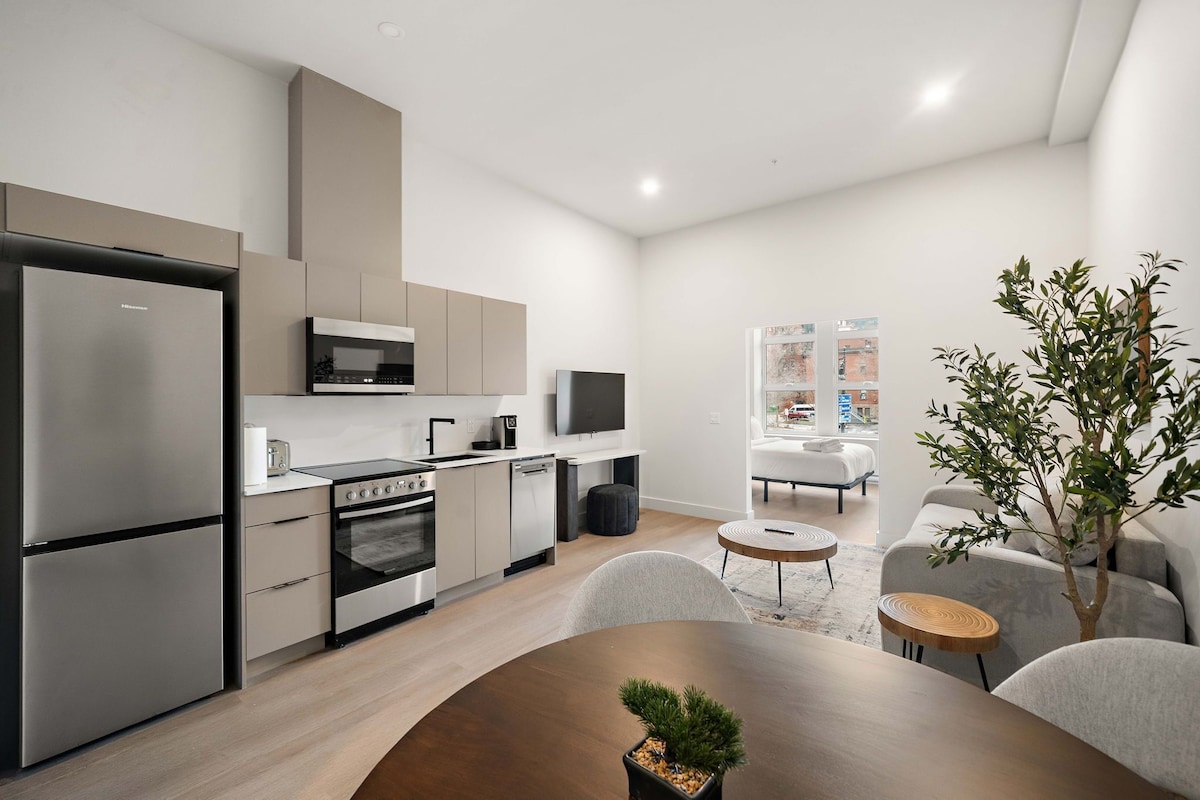 Eine moderne Küche mit Kühlschrank, Backofen, Mikrowelle und einem Essbereich mit Tisch und Stühlen.