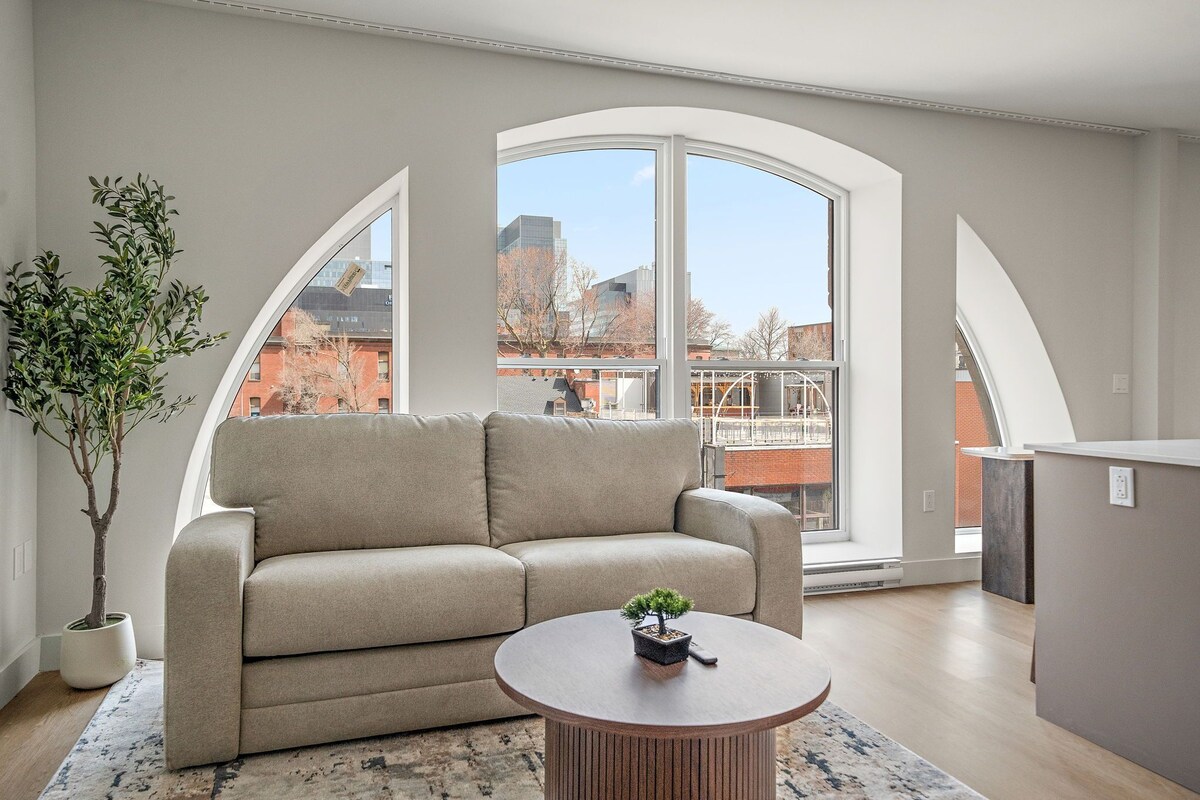 Ein modernes Wohnzimmer mit einer Couch, einem kleinen Tisch und einer Topfpflanze.
