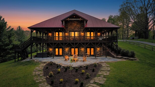 A two-story lodge with a stone facade, a red roof, and a balcony with outdoor seating. - 5BR Cabin on 3 Acres w Theater, Hot Tub +Fire Pit (Boone)
