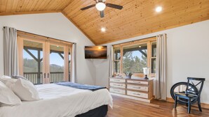 A bedroom with a bed, dresser, chair, and a TV on the wall. - 5BR Cabin on 3 Acres w Theater, Hot Tub +Fire Pit (Boone)