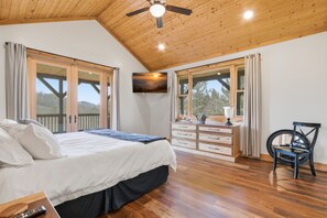 Ein Schlafzimmer mit Bett, Schminktisch, Sessel und Fernseher an der Wand.
