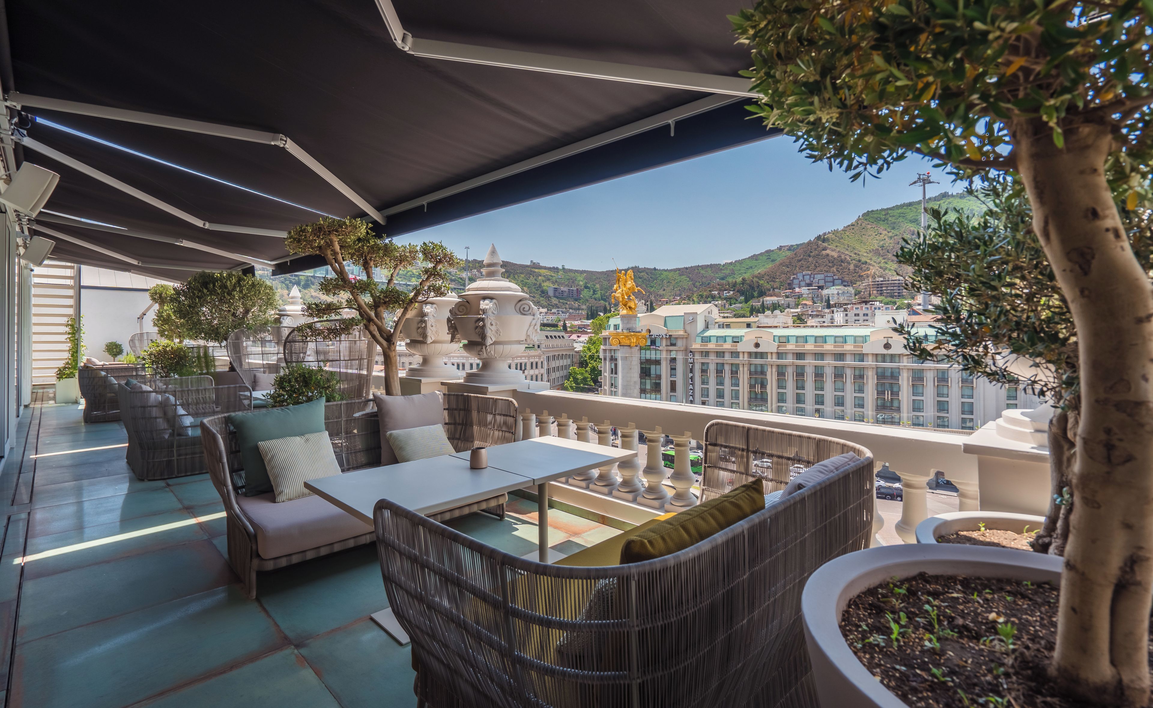 Une terrasse extérieure avec des meubles en osier, une table et des plantes en pot.