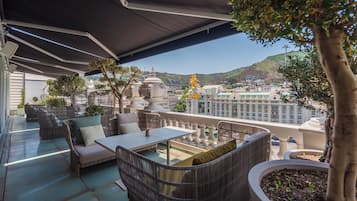 Eine Terrasse im Freien mit Korbmöbeln, einem Tisch und Kübelpflanzen.