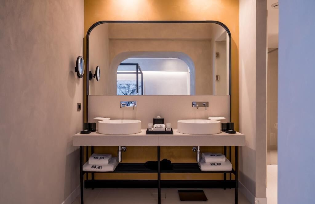 A modern bathroom with a large mirror, two sinks, and a shower.